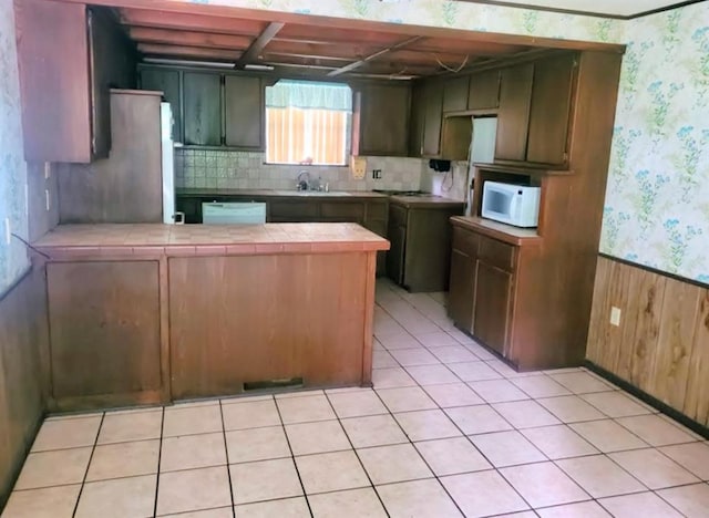 17 S Cemetery Rd, Tuttle, OK 73089 - kitchen featuring tile countertops, white appliances, a peninsula, a sink, and wallpapered walls