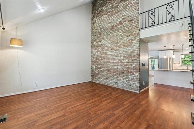 2220 NW 47th St, Oklahoma City, OK 73112 - unfurnished living room with brick wall, a towering ceiling, and wood finished floors