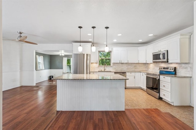 2220 NW 47th St, Oklahoma City, OK 73112 - kitchen with stainless steel appliances, a kitchen island, wood finished floors, light stone countertops, and recessed lighting