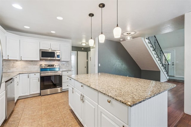 2220 NW 47th St, Oklahoma City, OK 73112 - kitchen featuring stainless steel appliances, tasteful backsplash, white cabinets, a center island, and light stone countertops
