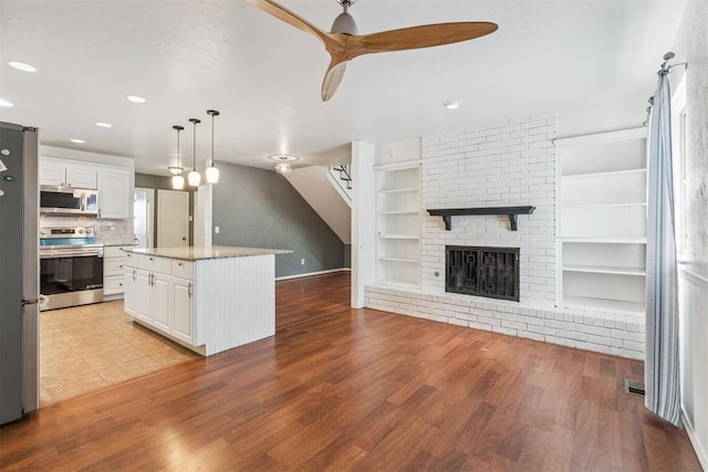 2220 NW 47th St, Oklahoma City, OK 73112 - kitchen with appliances with stainless steel finishes, open floor plan, white cabinets, built in shelves, and light wood-type flooring