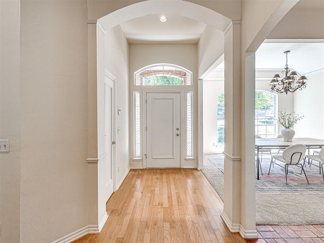 2417 Pawnee Xing, Edmond, OK 73034 - foyer with arched walkways, a chandelier, light wood-type flooring, and baseboards