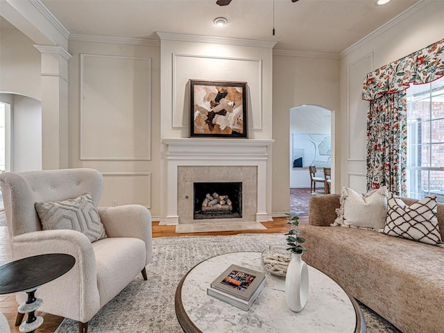 2417 Pawnee Xing, Edmond, OK 73034 - living area featuring arched walkways, crown molding, wood finished floors, ceiling fan, and a fireplace