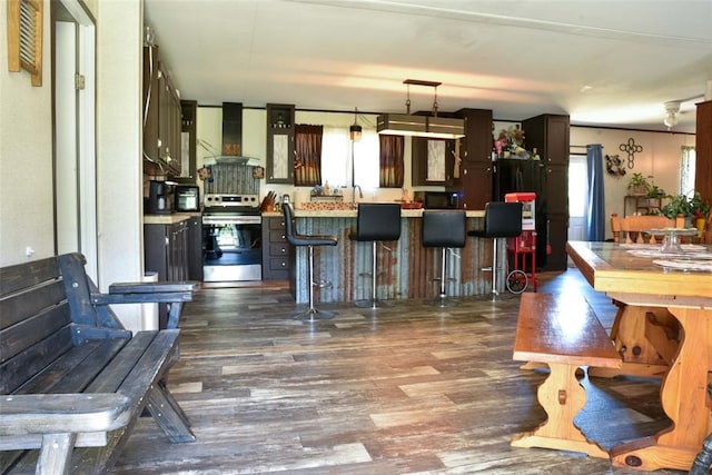 300746 Mcaly Rd, Foster, OK 73434 - kitchen featuring stainless steel electric stove, wall chimney exhaust hood, dark wood-style floors, and light countertops