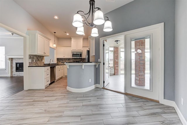 kitchen with an inviting chandelier, a sink, dark countertops, stainless steel appliances, and backsplash