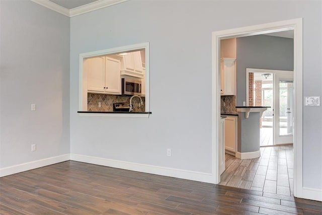 interior space with baseboards, ornamental molding, and wood finished floors