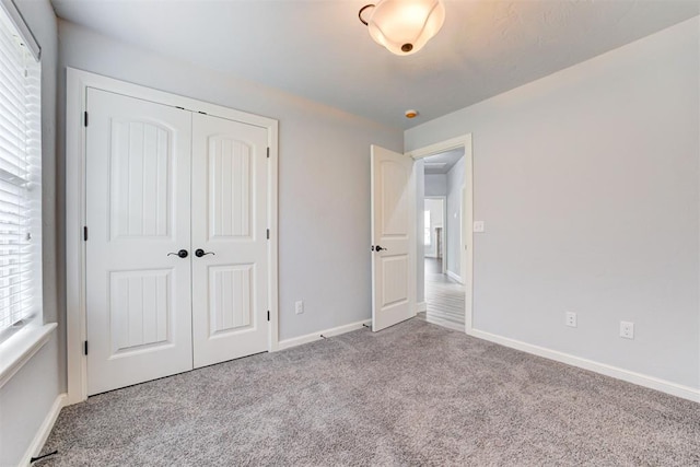 unfurnished bedroom with a closet, baseboards, and carpet floors