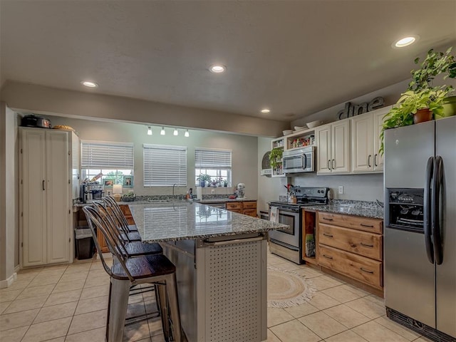 1072 County St Unit 2958, Tuttle, OK 73089 - kitchen with appliances with stainless steel finishes, light tile patterned floors, dark stone countertops, recessed lighting, and a kitchen bar