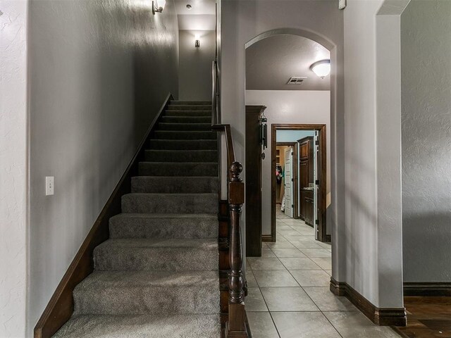 1808 Lago Dr, Moore, OK 73160 - stairs featuring arched walkways, baseboards, and tile patterned floors