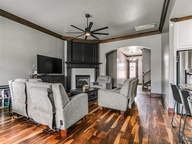 1808 Lago Dr, Moore, OK 73160 - living room with crown molding, arched walkways, a ceiling fan, a fireplace, and dark wood finished floors