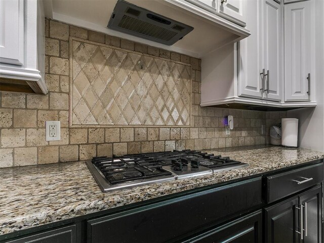 1808 Lago Dr, Moore, OK 73160 - kitchen with stainless steel gas cooktop, dark cabinetry, white cabinetry, tasteful backsplash, and exhaust hood