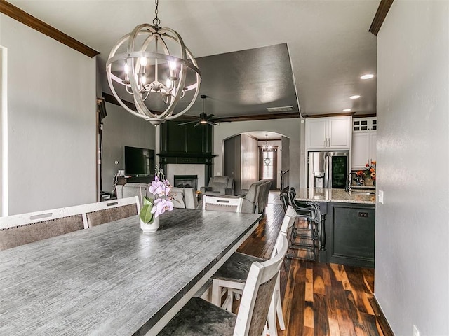 1808 Lago Dr, Moore, OK 73160 - dining area with a chandelier, ceiling fan, crown molding, arched walkways, and a large fireplace