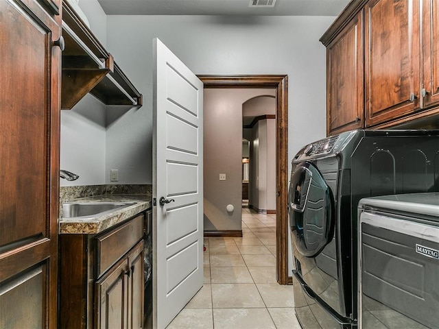 1808 Lago Dr, Moore, OK 73160 - laundry area with cabinet space, washer and clothes dryer, arched walkways, light tile patterned floors, and baseboards