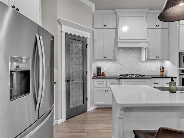 8332 Poplar Dr, Edmond, OK 73034 - kitchen with appliances with stainless steel finishes, light wood-type flooring, white cabinetry, decorative backsplash, and a breakfast bar