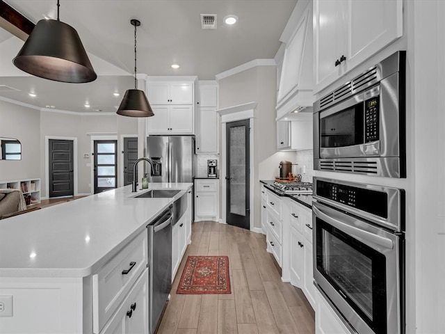 8332 Poplar Dr, Edmond, OK 73034 - kitchen featuring appliances with stainless steel finishes, light wood-type flooring, tasteful backsplash, white cabinetry, and hanging light fixtures