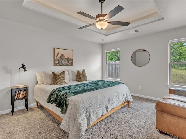8332 Poplar Dr, Edmond, OK 73034 - carpeted bedroom with a raised ceiling, multiple windows, and ceiling fan