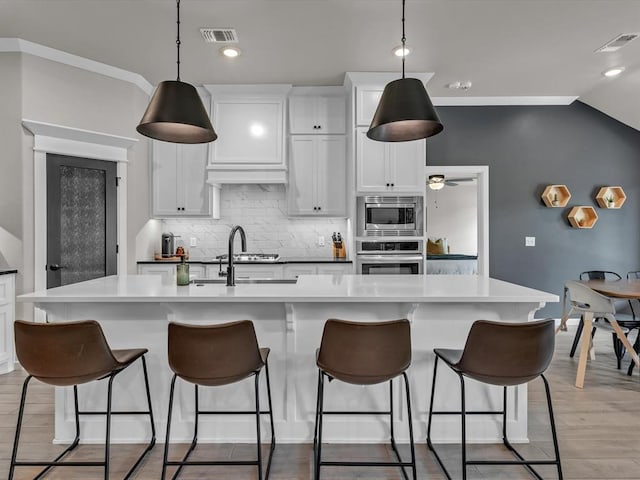 8332 Poplar Dr, Edmond, OK 73034 - kitchen featuring appliances with stainless steel finishes, decorative backsplash, white cabinetry, ceiling fan, and hanging light fixtures