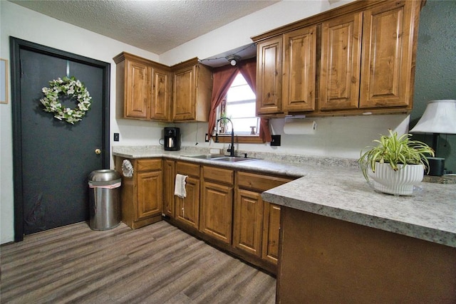1208 Cathy Ln, Oklahoma City, OK 73110 - kitchen featuring a sink, wood finished floors, brown cabinetry, a textured ceiling, and light countertops