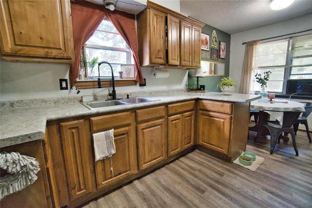 1208 Cathy Ln, Oklahoma City, OK 73110 - kitchen featuring a sink, wood finished floors, brown cabinets, light countertops, and a textured ceiling