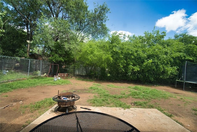 1208 Cathy Ln, Oklahoma City, OK 73110 - view of yard featuring a trampoline, a fire pit, fence, and a patio area