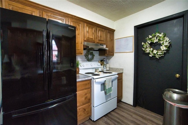 1208 Cathy Ln, Oklahoma City, OK 73110 - kitchen with freestanding refrigerator, electric stove, under cabinet range hood, dark wood finished floors, and decorative backsplash