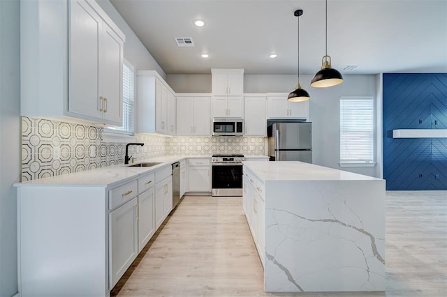 kitchen featuring appliances with stainless steel finishes, a kitchen island, a sink, light wood-type flooring, and recessed lighting