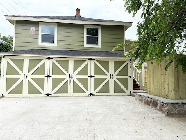 view of outbuilding with fence and concrete driveway