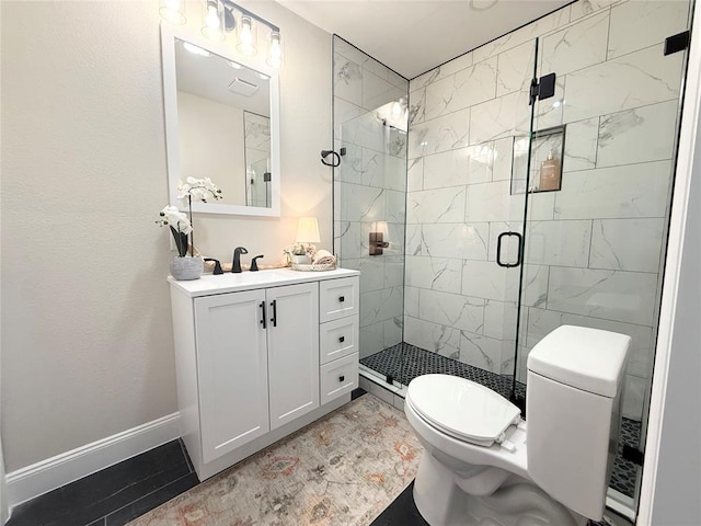 bathroom with toilet, a shower stall, baseboards, and vanity