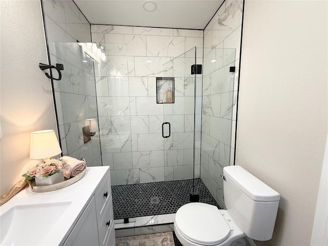 bathroom featuring a shower stall, toilet, vanity, and a textured wall