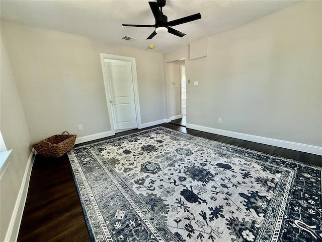 unfurnished room with dark wood-style flooring, ceiling fan, and baseboards