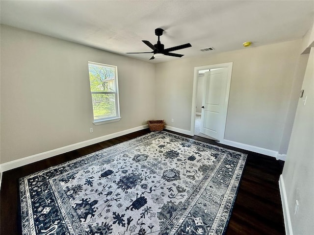 empty room with dark wood finished floors, baseboards, and ceiling fan