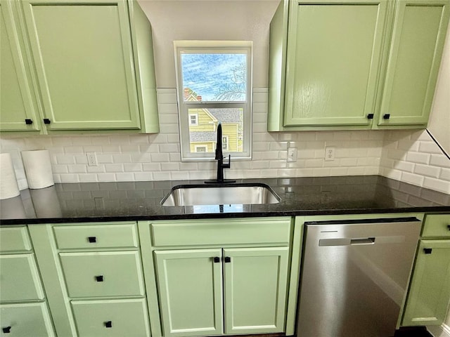 kitchen featuring stainless steel dishwasher, green cabinetry, a sink, backsplash, and dark stone countertops
