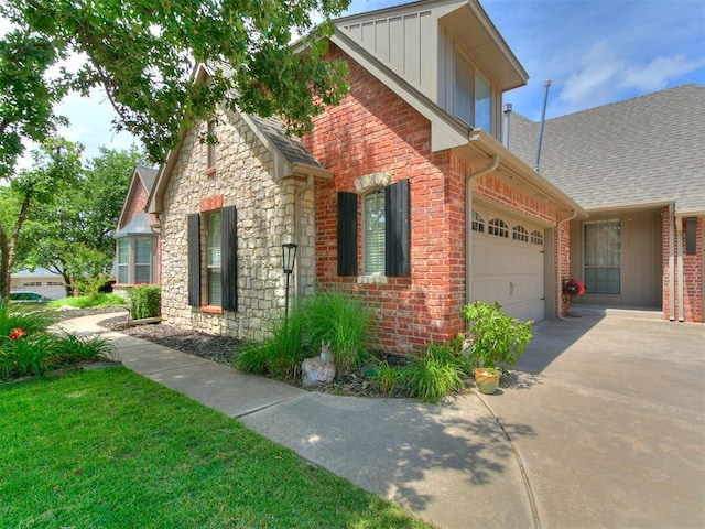 3133 Beacon Hill St, Edmond, OK 73034 - view of front of property featuring concrete driveway, stone siding, brick siding, an attached garage, and board and batten siding