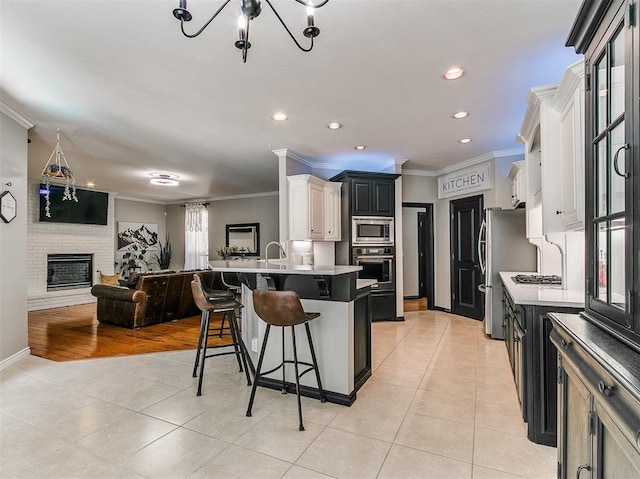 3133 Beacon Hill St, Edmond, OK 73034 - kitchen featuring stainless steel appliances, ornamental molding, light tile patterned flooring, a kitchen bar, and open floor plan