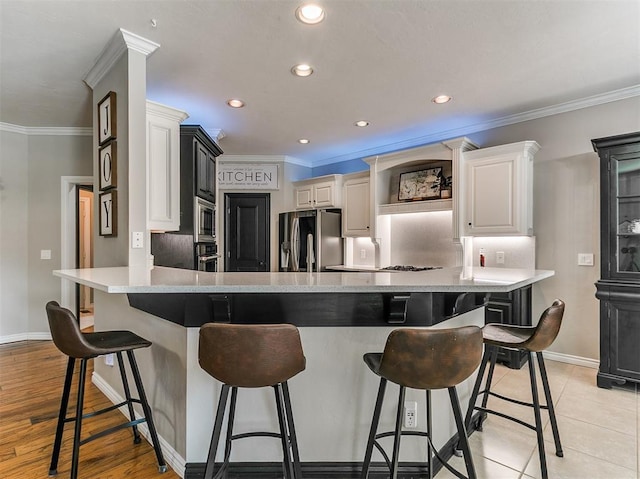 3133 Beacon Hill St, Edmond, OK 73034 - kitchen with appliances with stainless steel finishes, crown molding, light countertops, a peninsula, and a breakfast bar area