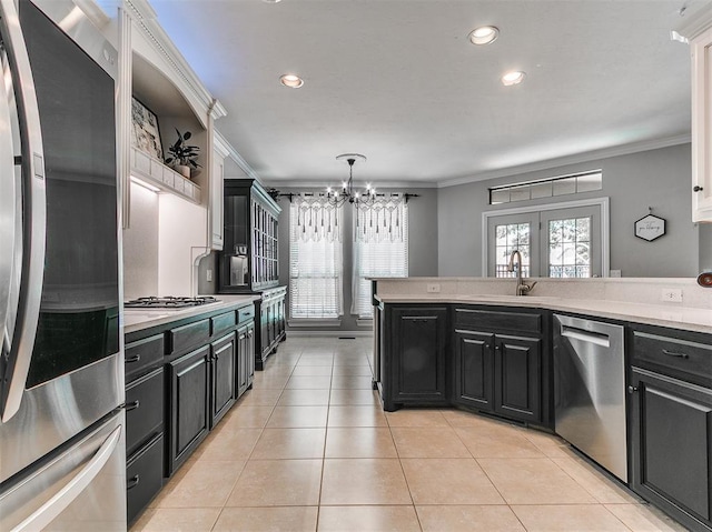 3133 Beacon Hill St, Edmond, OK 73034 - kitchen with stainless steel appliances, ornamental molding, a chandelier, light countertops, and dark cabinetry
