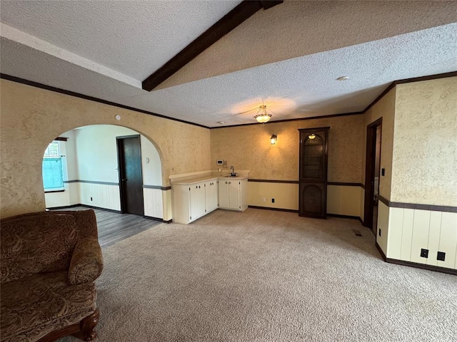 804 William Blvd, Seminole, OK 74868 - unfurnished living room featuring light colored carpet, a textured ceiling, crown molding, arched walkways, and wallpapered walls