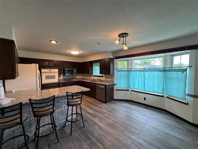 804 William Blvd, Seminole, OK 74868 - kitchen with a sink, a peninsula, wood finished floors, dark brown cabinetry, and appliances with stainless steel finishes