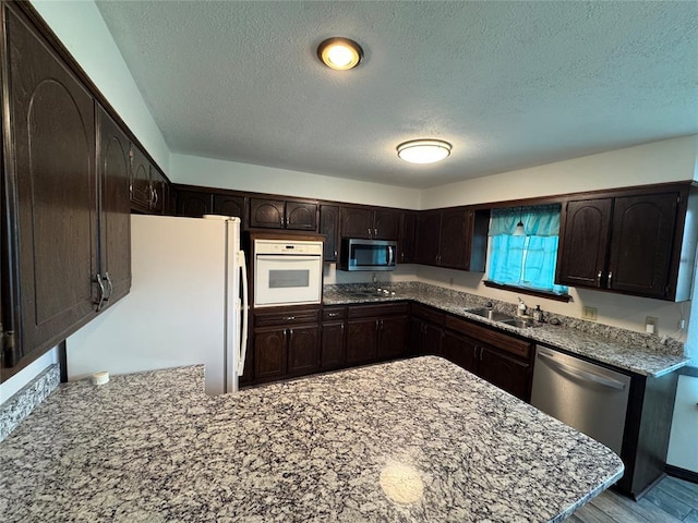 804 William Blvd, Seminole, OK 74868 - kitchen with a textured ceiling, a sink, dark brown cabinetry, a peninsula, and stainless steel appliances