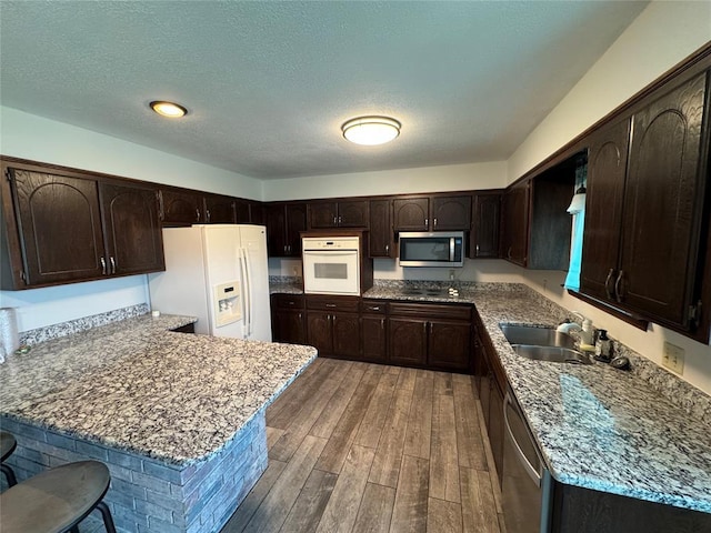 804 William Blvd, Seminole, OK 74868 - kitchen with a peninsula, appliances with stainless steel finishes, dark brown cabinets, and wood finished floors