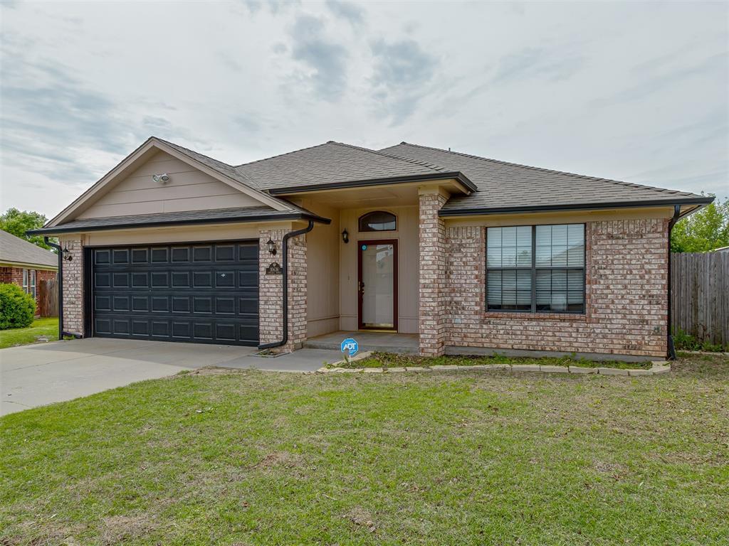ranch-style house featuring a garage, fence, concrete driveway, a front lawn, and brick siding