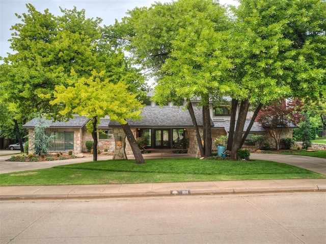 1011 Saint Andrews Dr, Edmond, OK 73025 - view of front facade featuring stone siding, a front yard, and roof with shingles