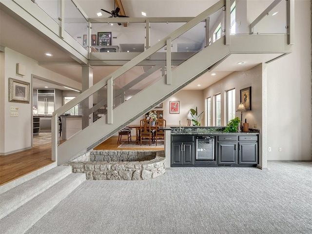 1011 Saint Andrews Dr, Edmond, OK 73025 - carpeted living room with stairway, a towering ceiling, beverage cooler, ceiling fan, and recessed lighting
