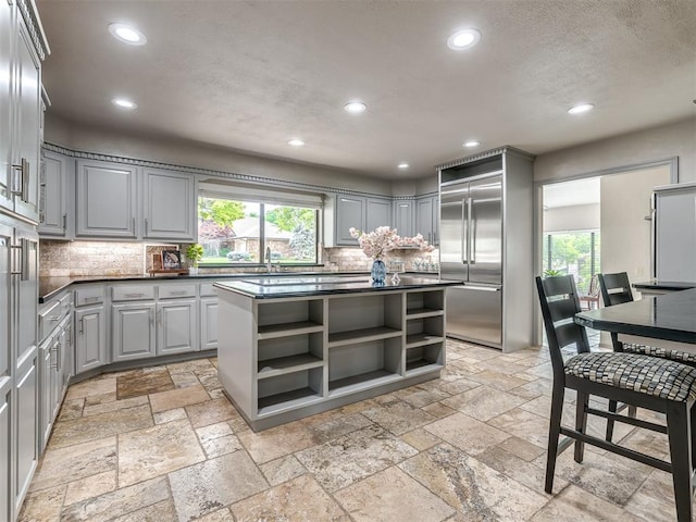 1011 Saint Andrews Dr, Edmond, OK 73025 - kitchen with gray cabinets, open shelves, built in fridge, dark countertops, and recessed lighting