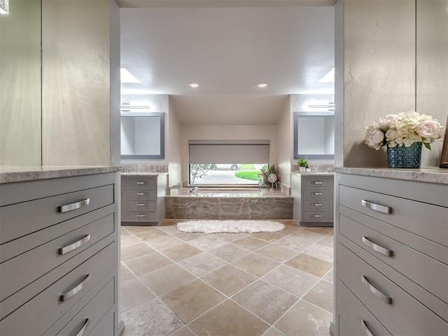 1011 Saint Andrews Dr, Edmond, OK 73025 - full bathroom with two vanities, a garden tub, stone tile flooring, and recessed lighting