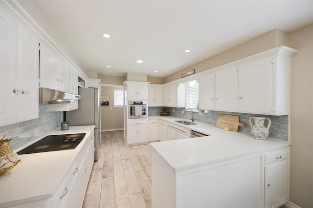 3205 NW 54th Cir, Oklahoma City, OK 73112 - kitchen with appliances with stainless steel finishes, under cabinet range hood, a peninsula, white cabinetry, and light wood-type flooring