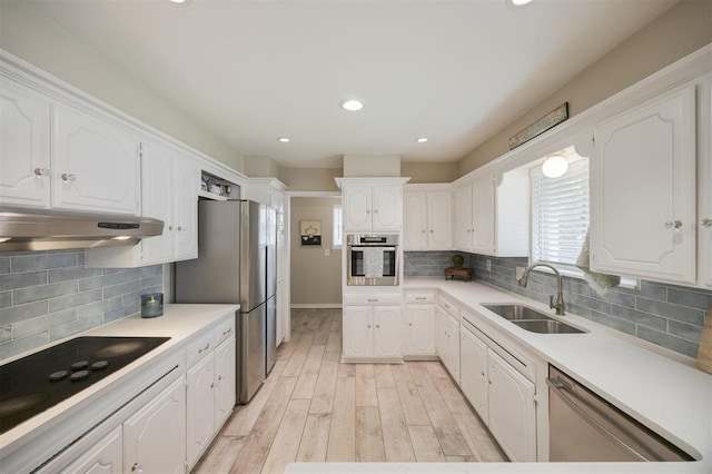 3205 NW 54th Cir, Oklahoma City, OK 73112 - kitchen featuring appliances with stainless steel finishes, under cabinet range hood, white cabinetry, light wood-style floors, and tasteful backsplash