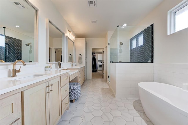bathroom featuring a shower stall, double vanity, a freestanding bath, tile patterned flooring, and tile walls