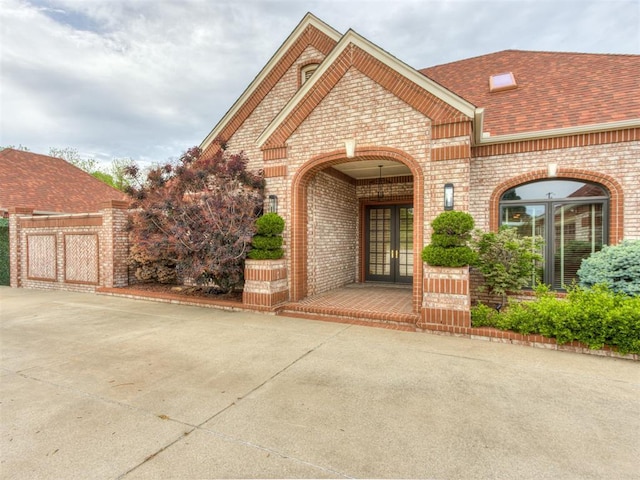 9408 S Caldwell Dr, Midwest City, OK 73130 - view of exterior entry with french doors, brick siding, and roof with shingles