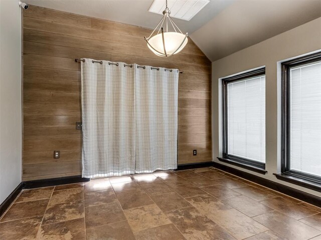 9408 S Caldwell Dr, Midwest City, OK 73130 - unfurnished dining area with lofted ceiling, wood walls, and baseboards